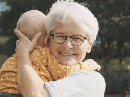 An elderly lady is holding a baby.