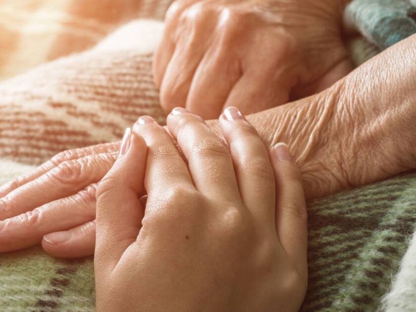 One person is holding a hand on another person's hand.