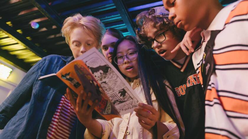 Several young people are looking at a magazine.