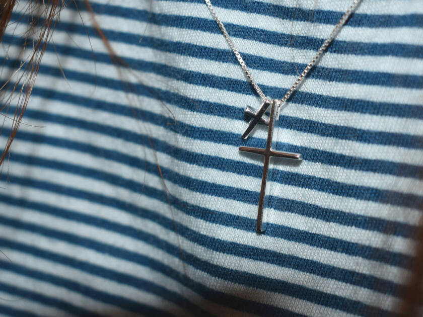 Two silver crosses around a persons neck.