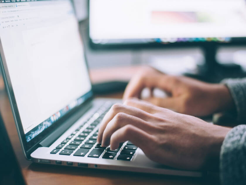 Hands typing on a laptop computer.