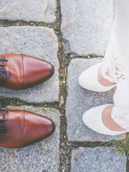 The feet of a bride and groom standing opposite each other.