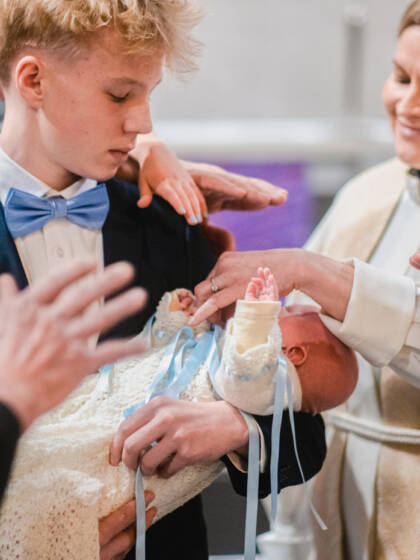 A priest is blessing a baby.