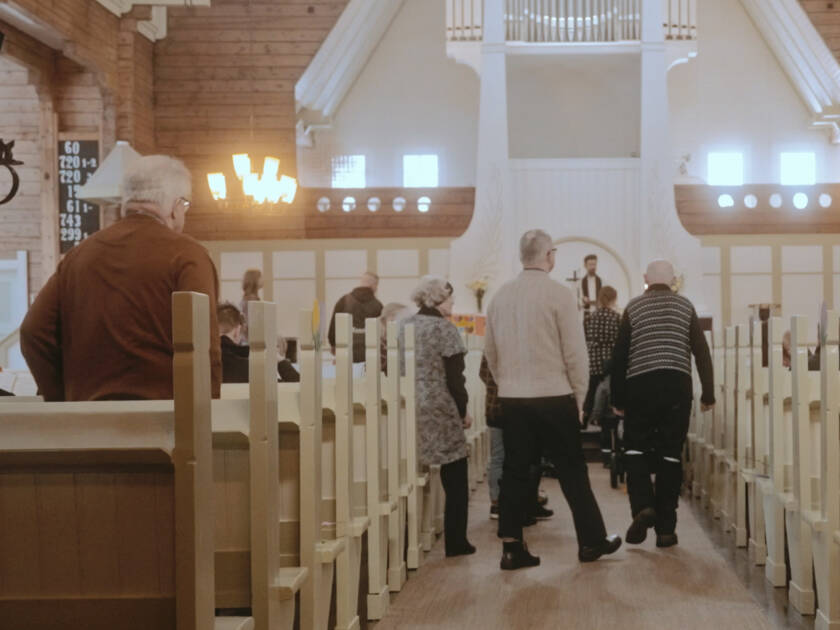 Människor går längs mittgången i en kyrka.